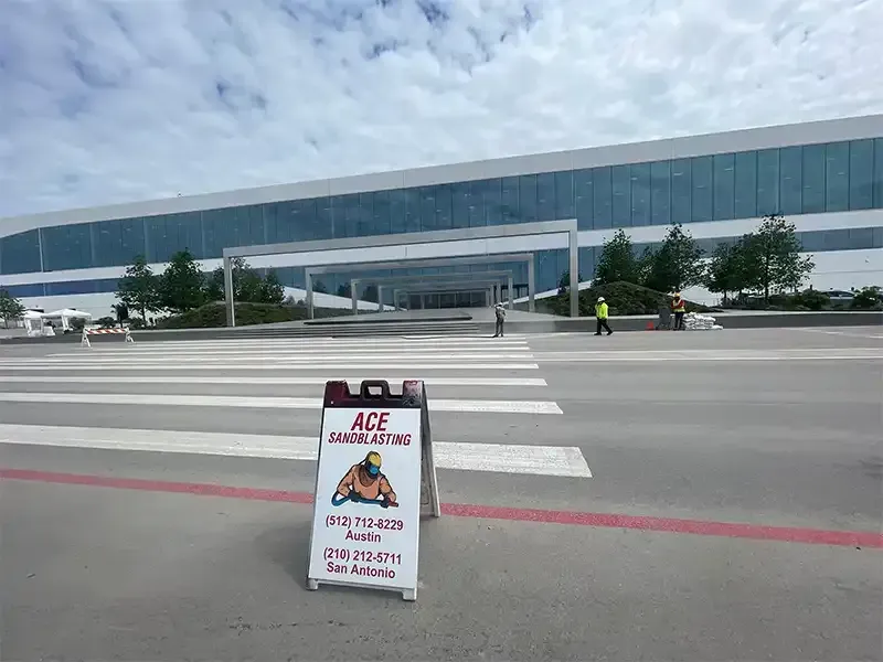 Ace Sandblasting sidewalk sign at a corporate campus parking lot
