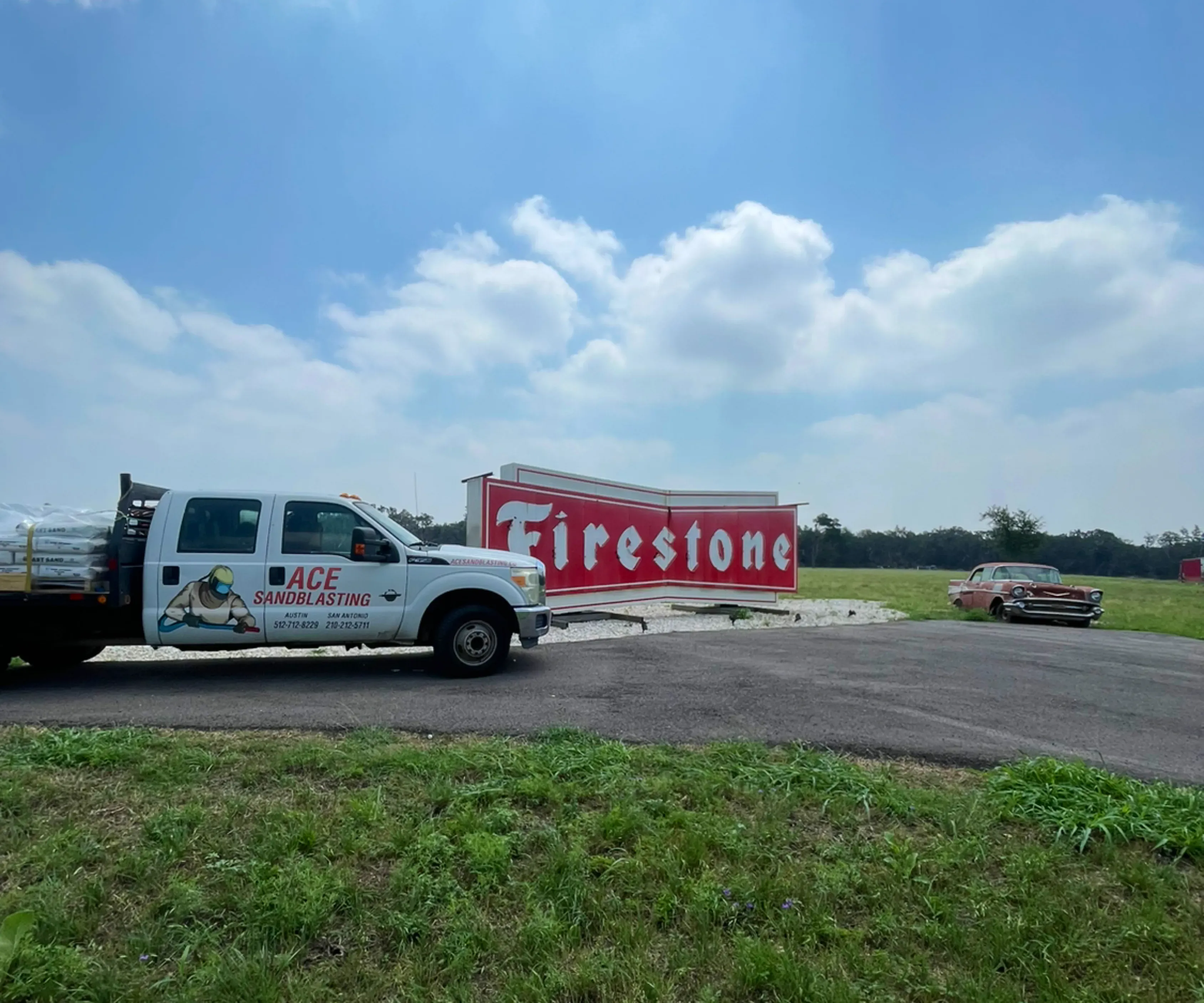 Ace Sandblasting flatbed work truck parked beside a Firestone building