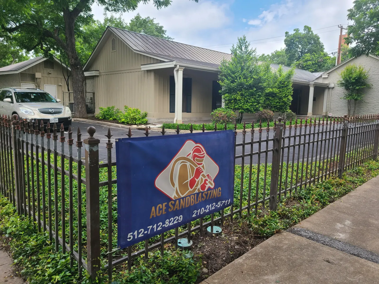 Ace Sandblasting yard sign on an iron fence at a commercial property
