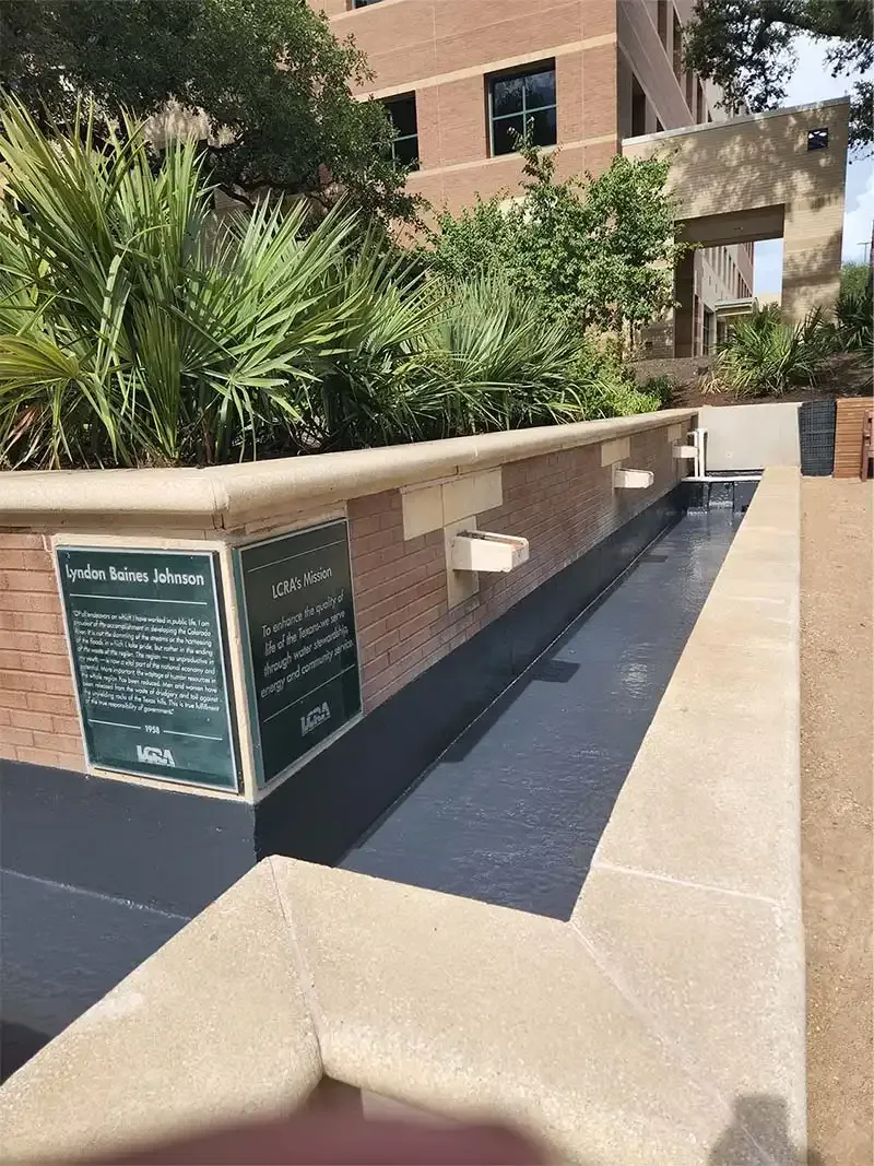 Brick planter ledge with a new black coating below memorial plaques