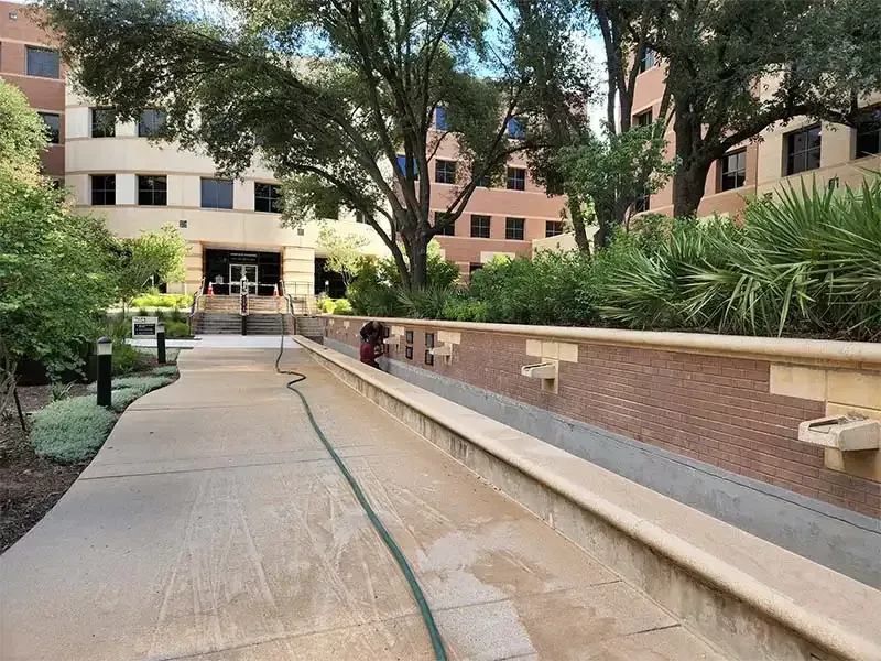 Brick planter wall along a campus walkway prepped for blasting