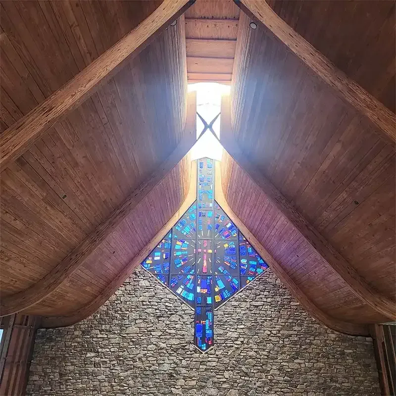 Sandblasted wood beams framing a blue stained glass church window