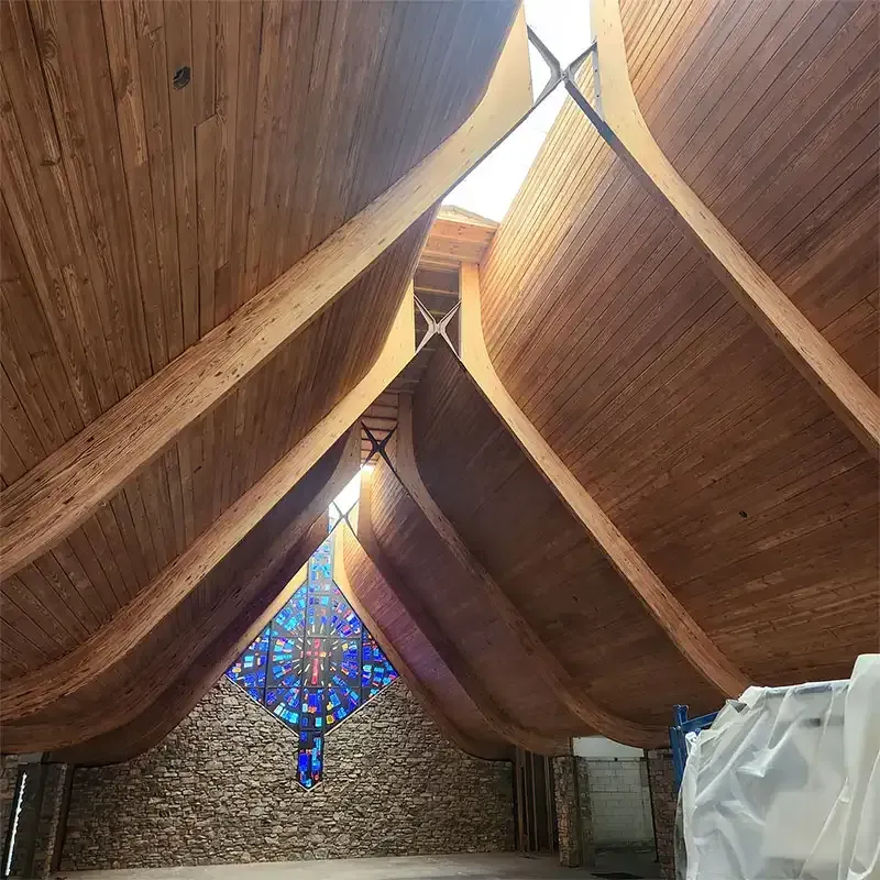 Arched wood ceiling and stained glass window inside a church