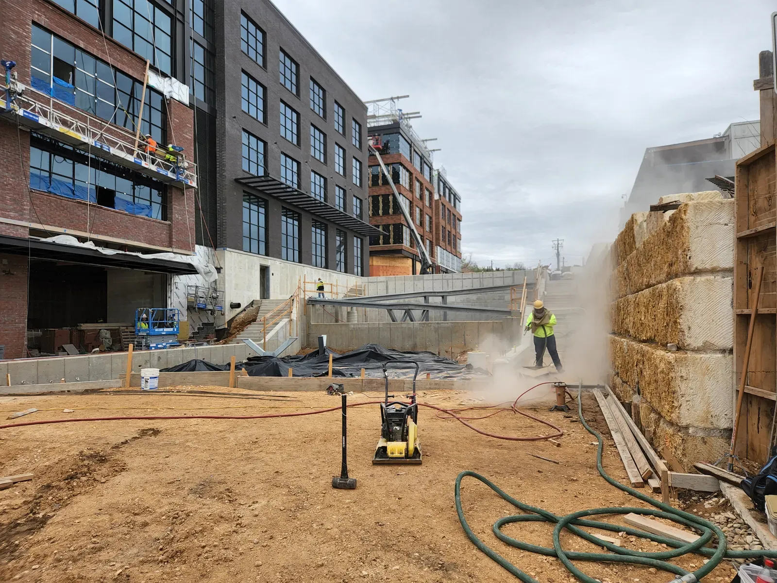 Crew sandblasting a retaining wall at a downtown construction site