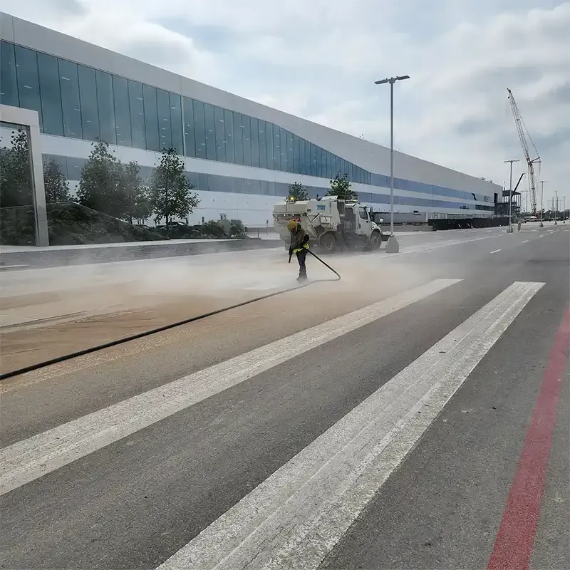 Crew sandblasting a crosswalk beside a glass office complex