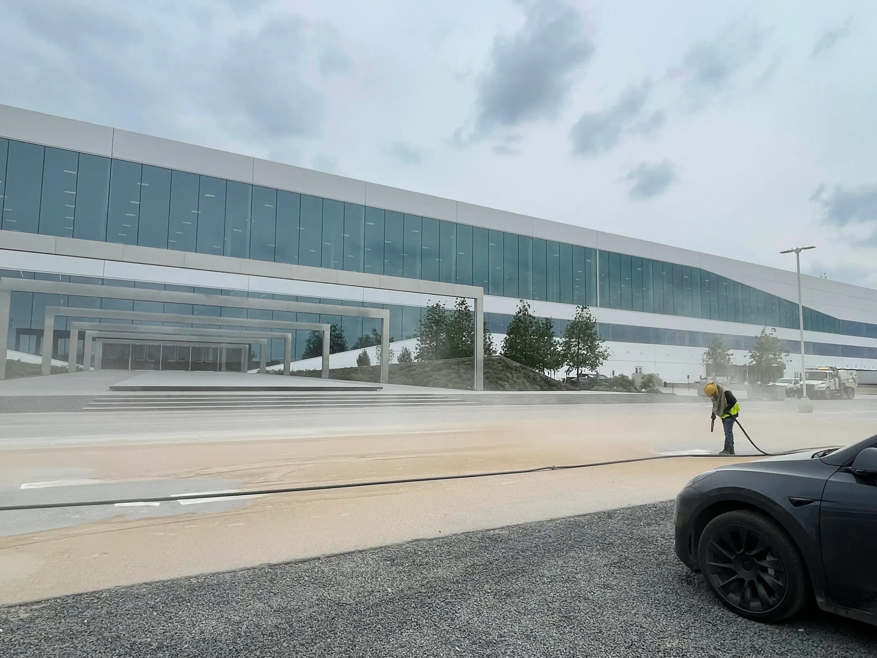 Crew blasting pavement outside a large glass corporate campus