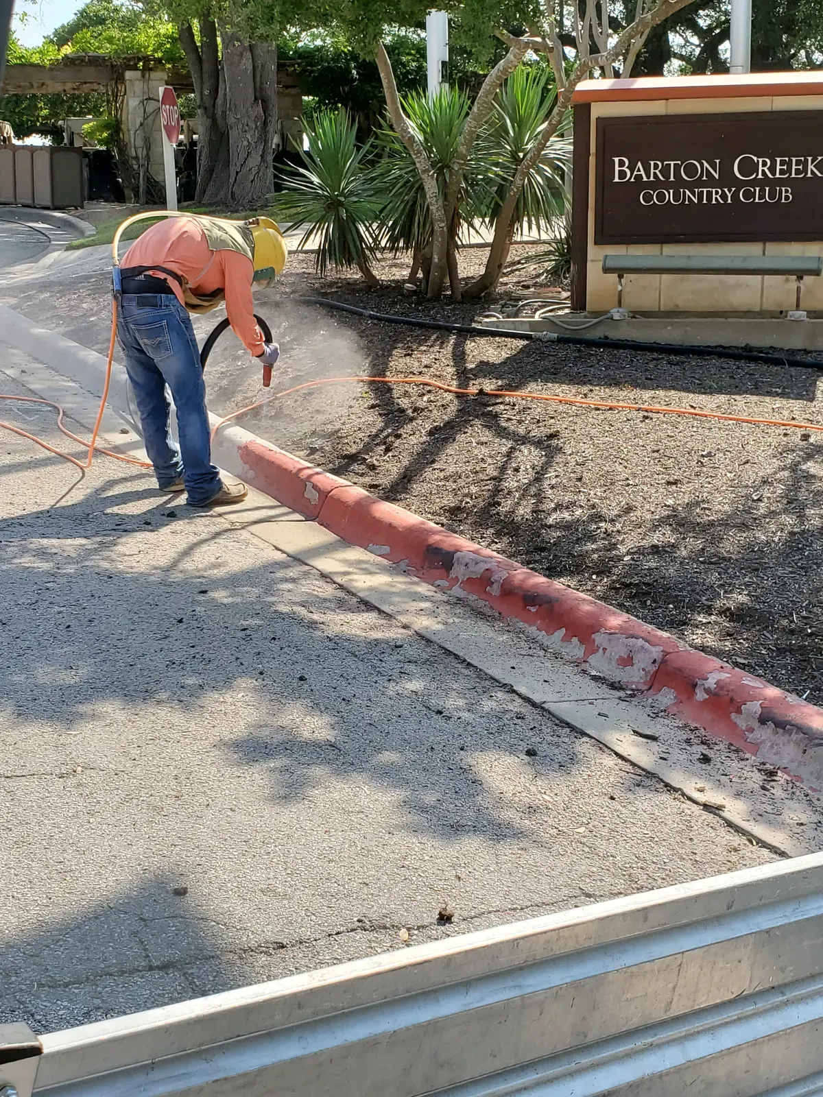 Ace technician blasting curb paint at a country club entrance