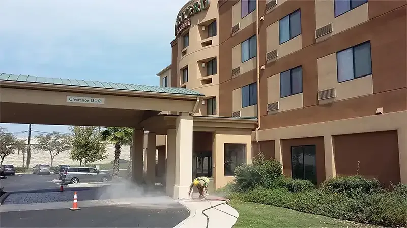 Sandblasting dust rising along a hotel driveway and covered entrance