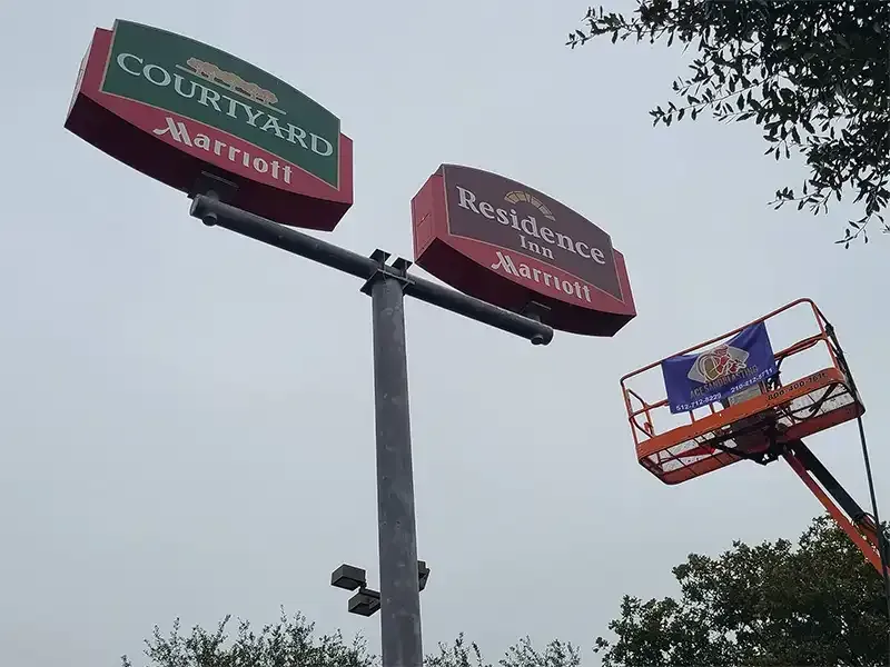 Lift crew preparing a Marriott hotel pylon sign for refinishing