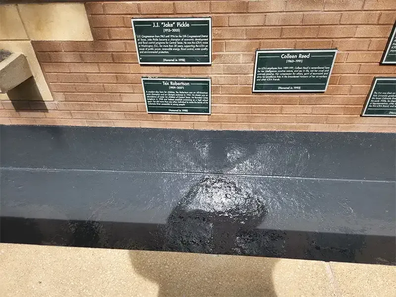 Close-up of memorial plaques above a freshly coated wall base