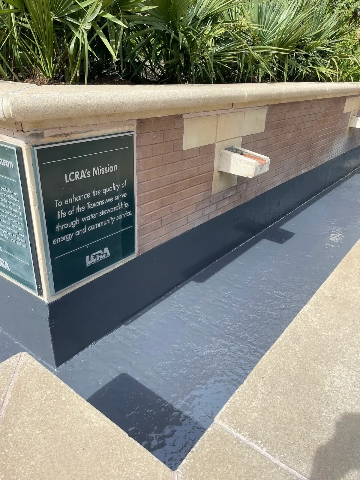 LCRA mission plaque above a freshly coated planter wall base