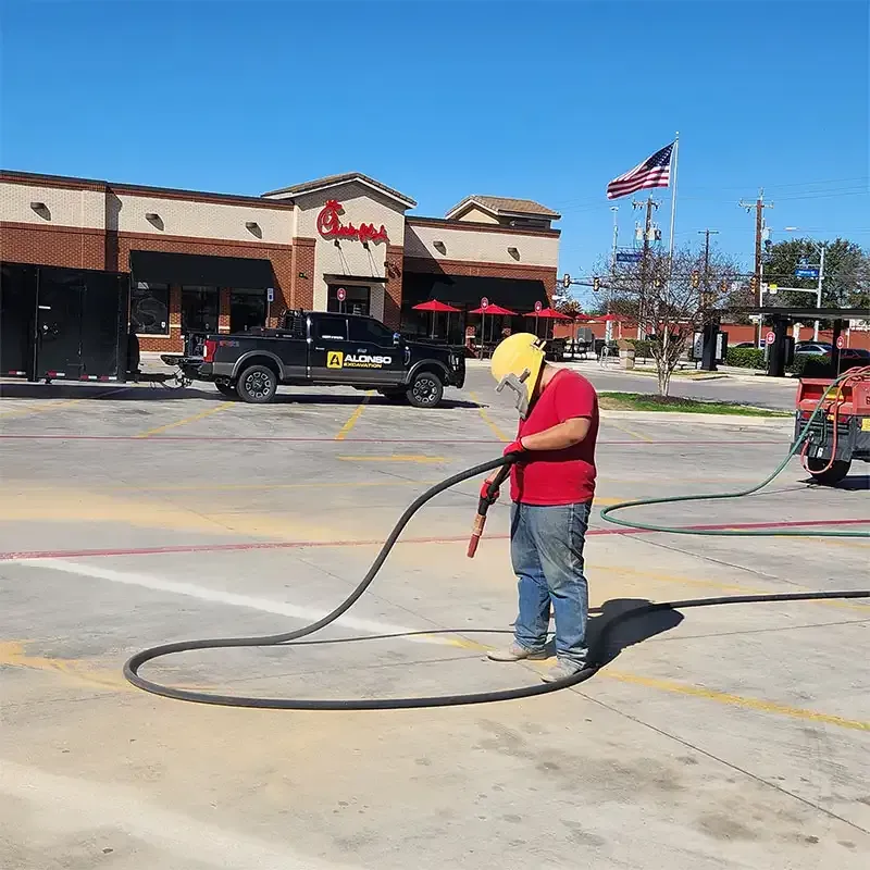 Technician sandblasting a parking lot outside a Chick-fil-A