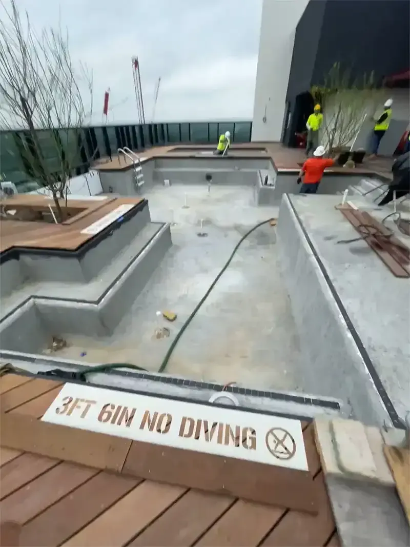 Crew prepping an empty rooftop pool with a city view