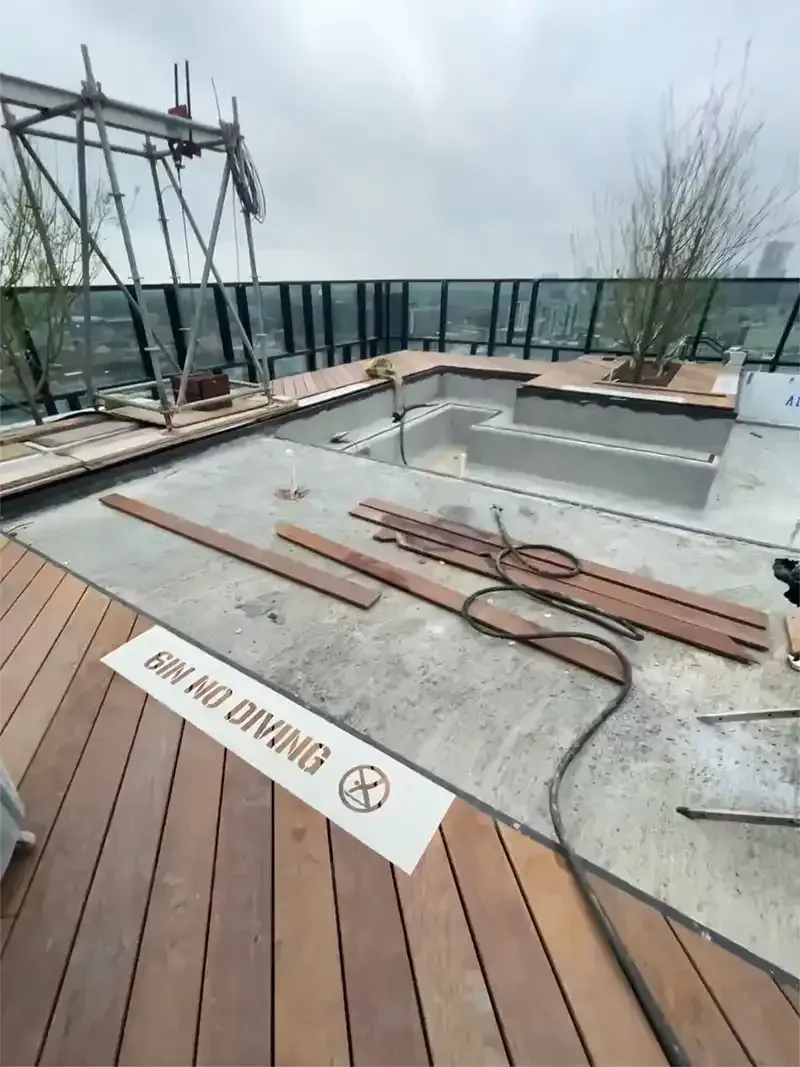 Empty rooftop pool shell and wood deck prepped for blasting