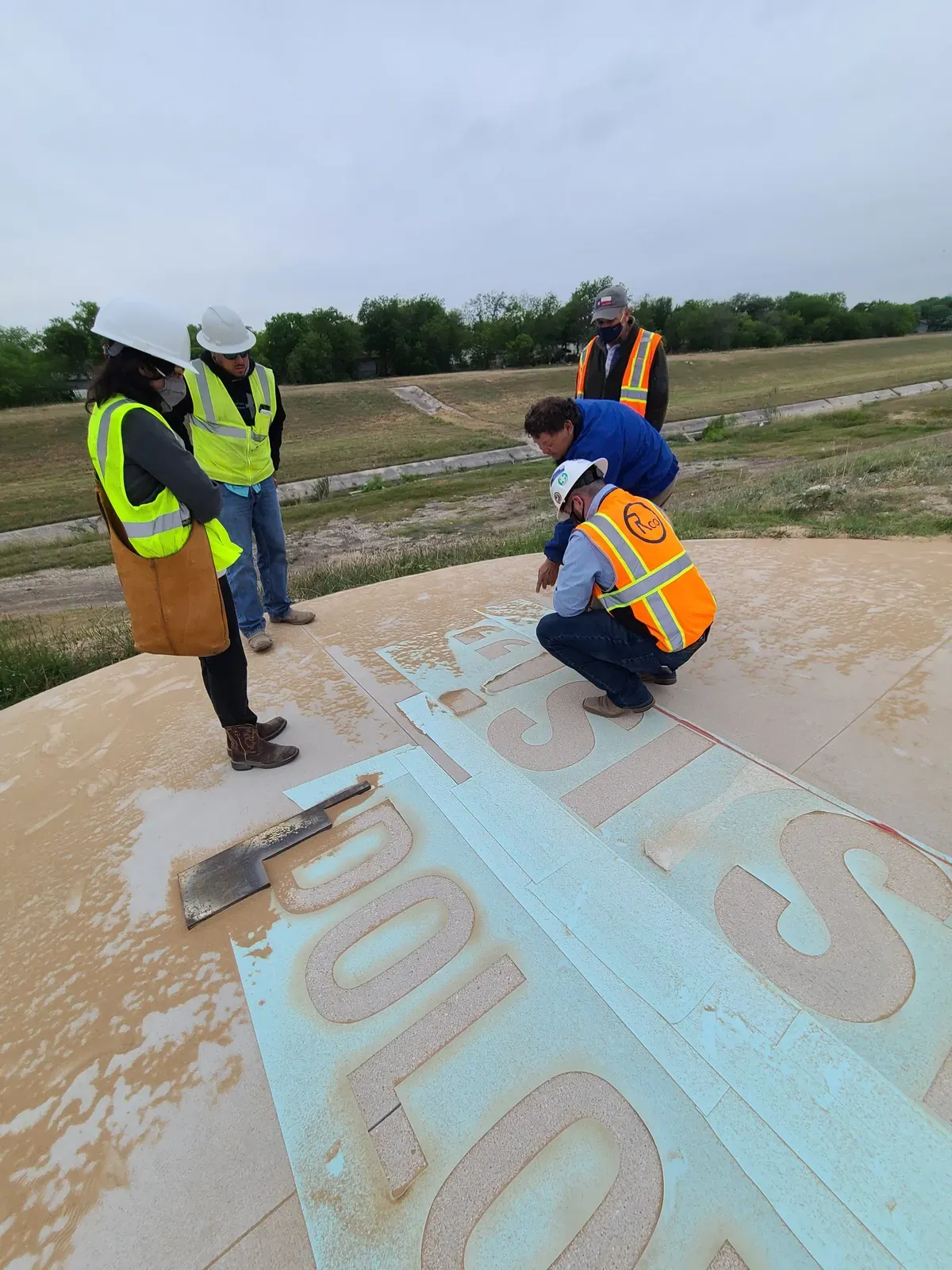 Crew inspecting sand-etched lettering on a concrete slab