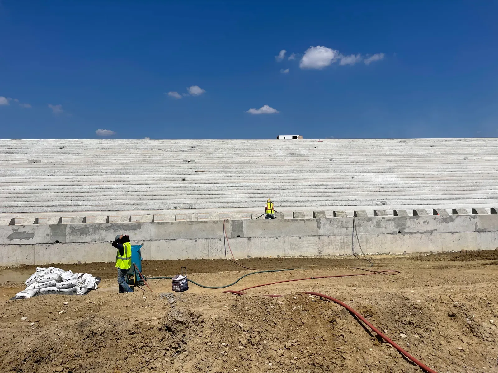 Crew sandblasting tiered concrete stadium seating