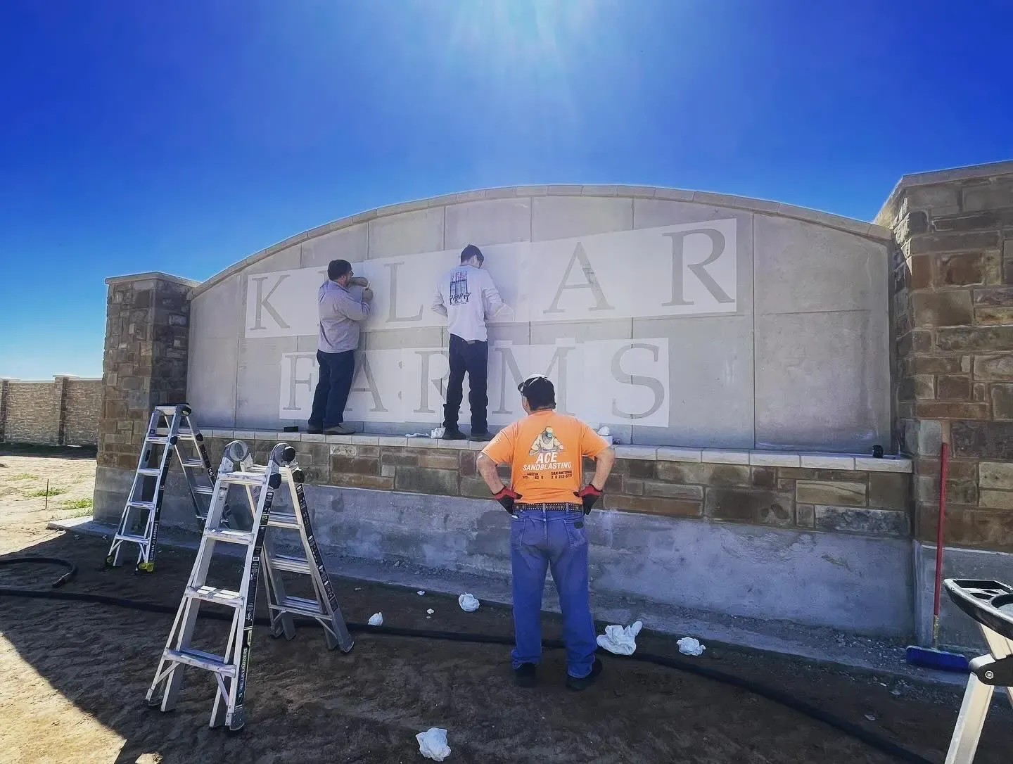 Crew on ladders refinishing the Kellar Farms subdivision entrance sign