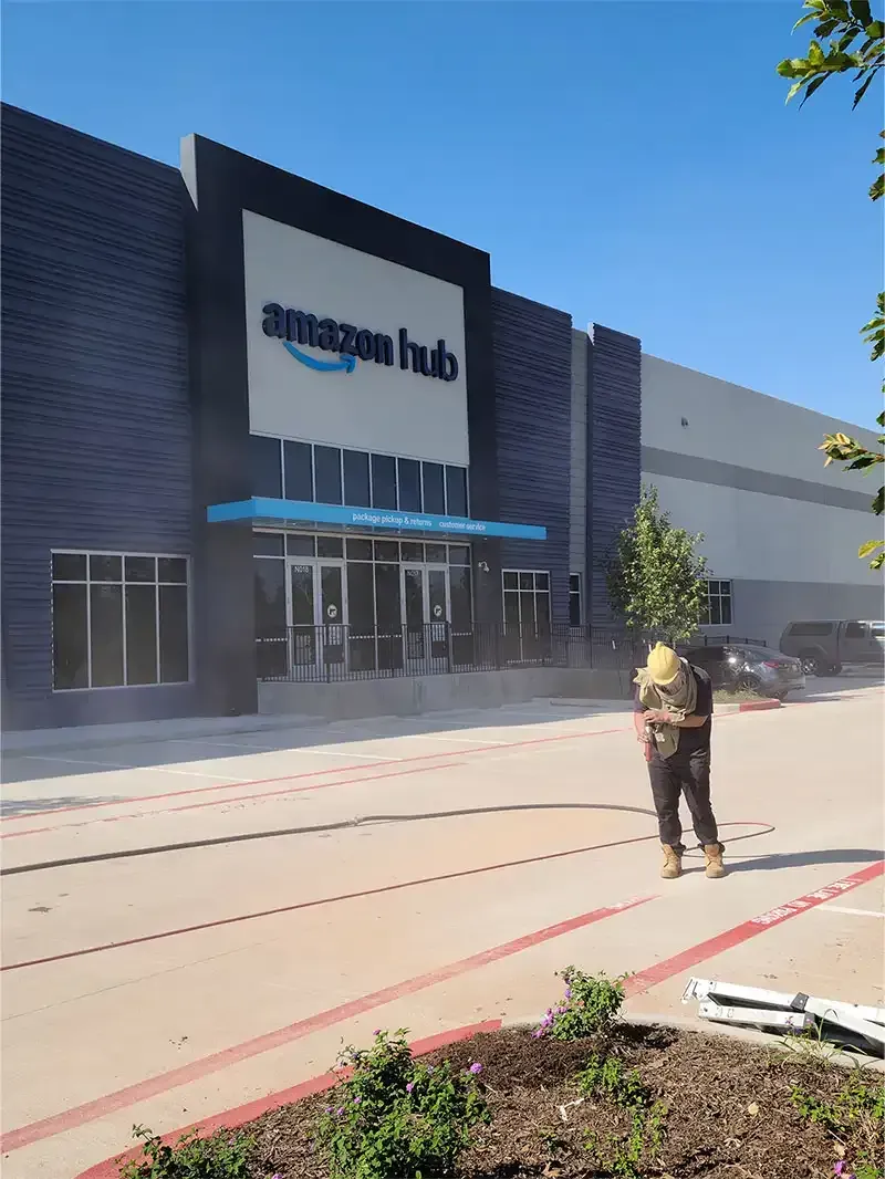 Crew member blasting striping paint outside an Amazon Hub building