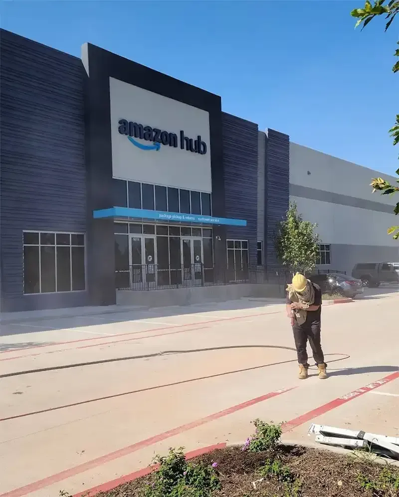 Technician blasting concrete at an Amazon Hub warehouse entrance