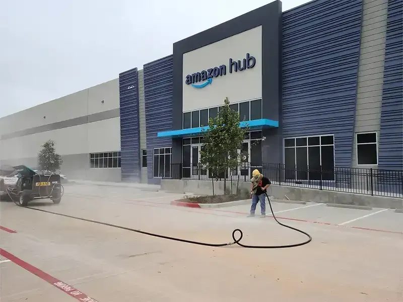 Technician sandblasting pavement at an Amazon Hub warehouse
