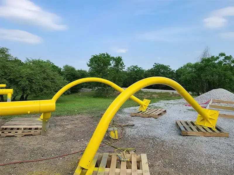Yellow-coated steel pipe arches on pallets after blasting and painting