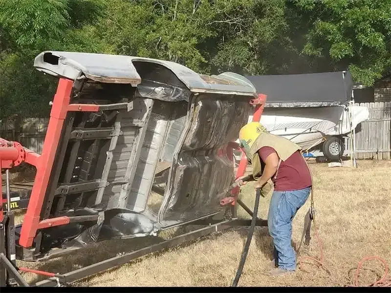 Technician blasting the underside of a car body on a rotisserie