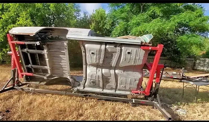 Classic car body on a red rotisserie after sandblasting