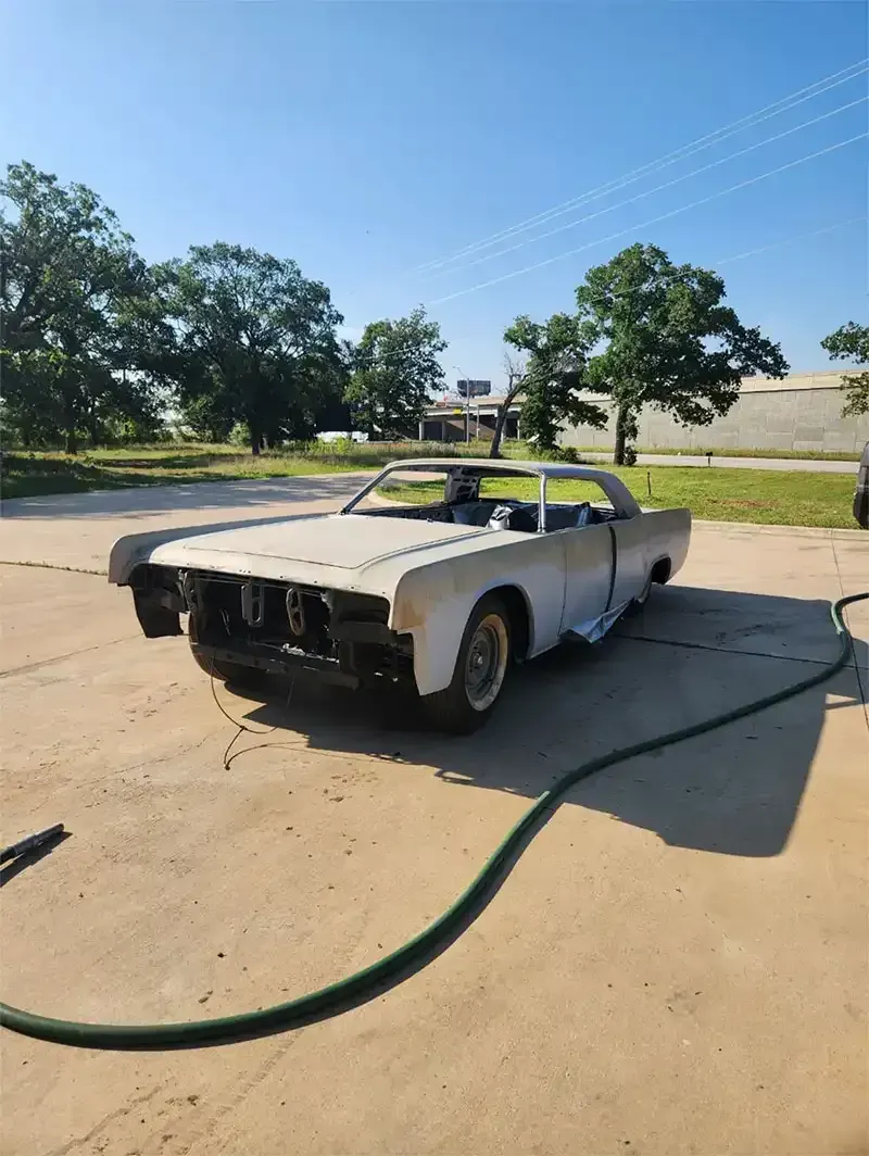 Classic sedan body stripped to bare metal on a concrete lot