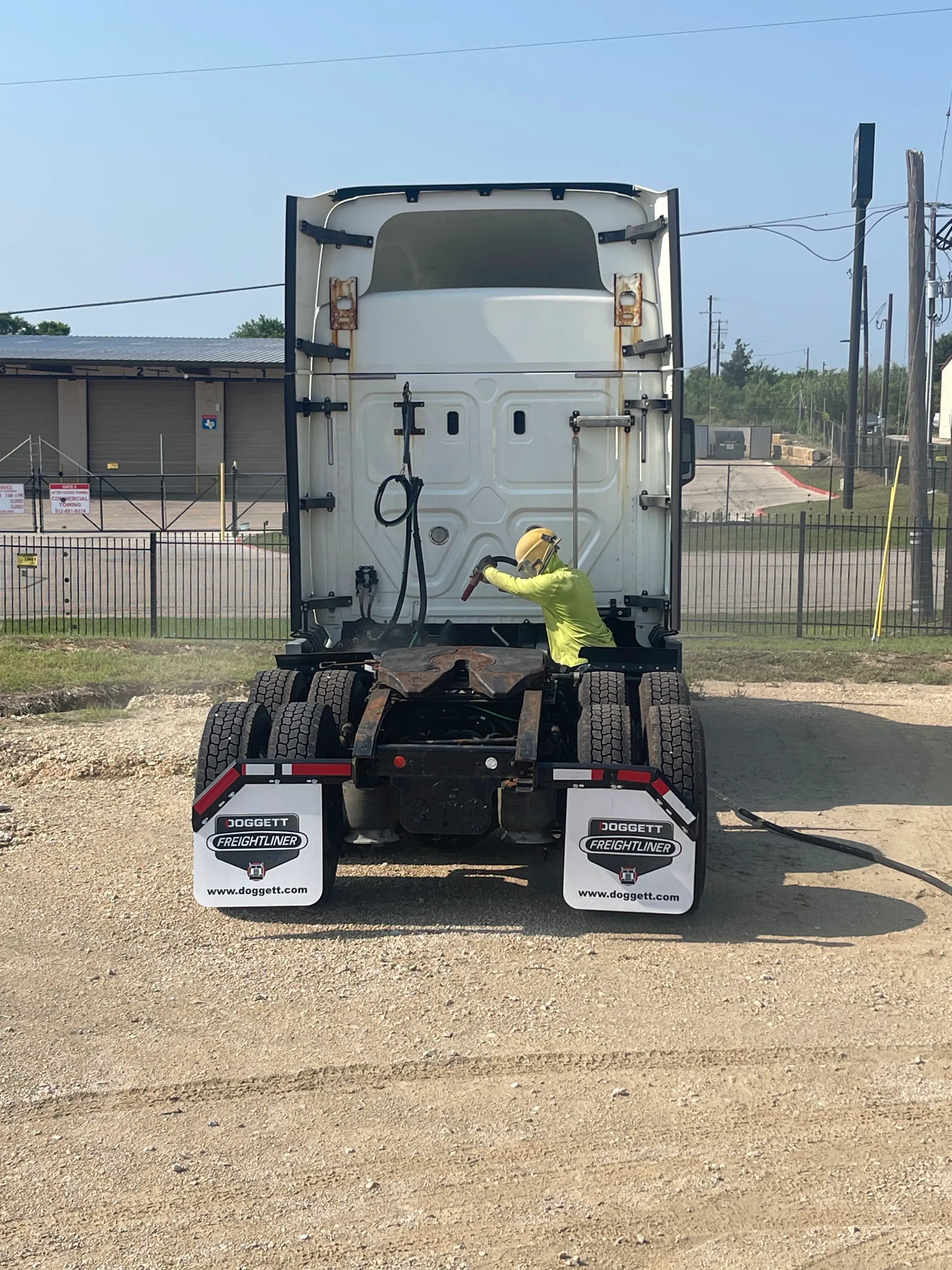 Technician sandblasting the back of a white semi-truck cab