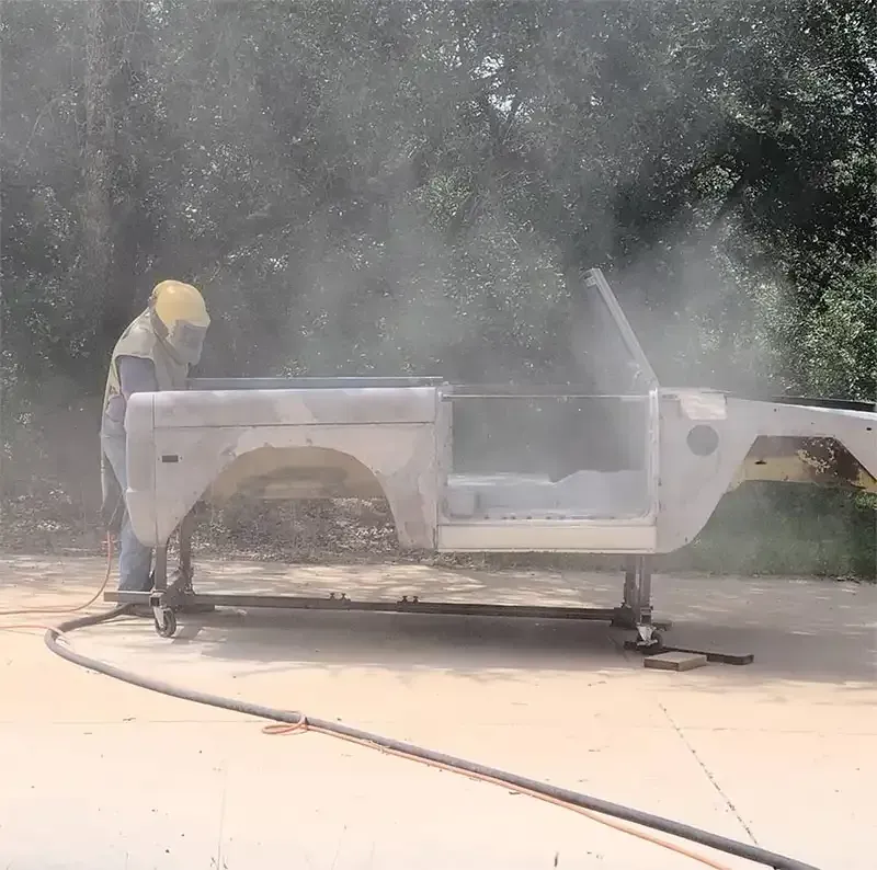 Blaster stripping a classic truck body in a cloud of media