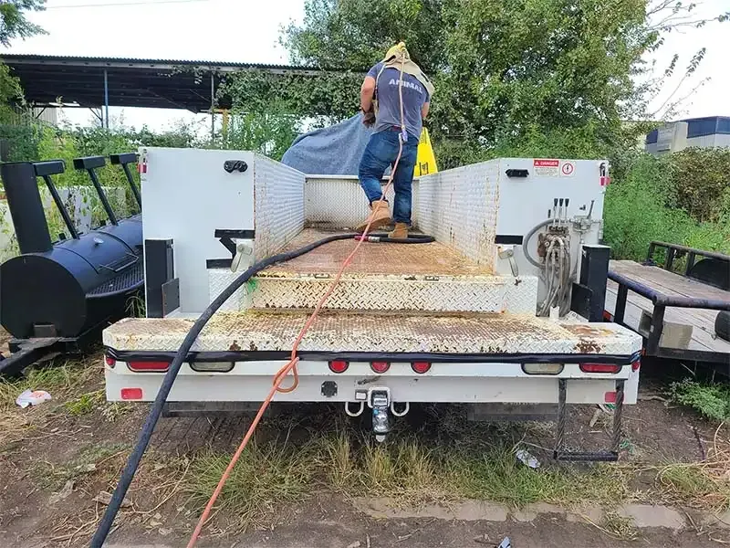 Technician sandblasting a utility truck flatbed and toolboxes