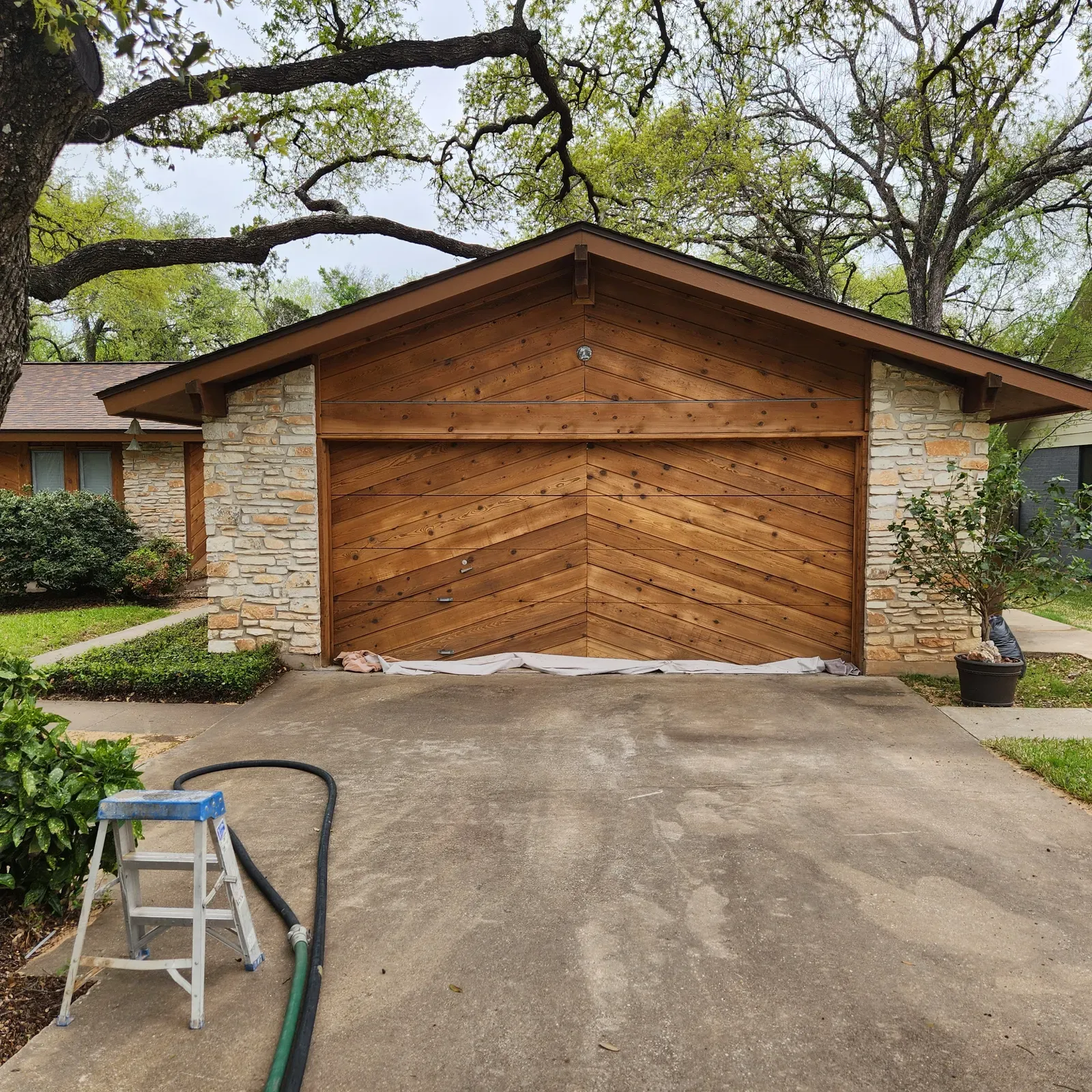 Residential project: restored cedar garage door on a stone ranch home