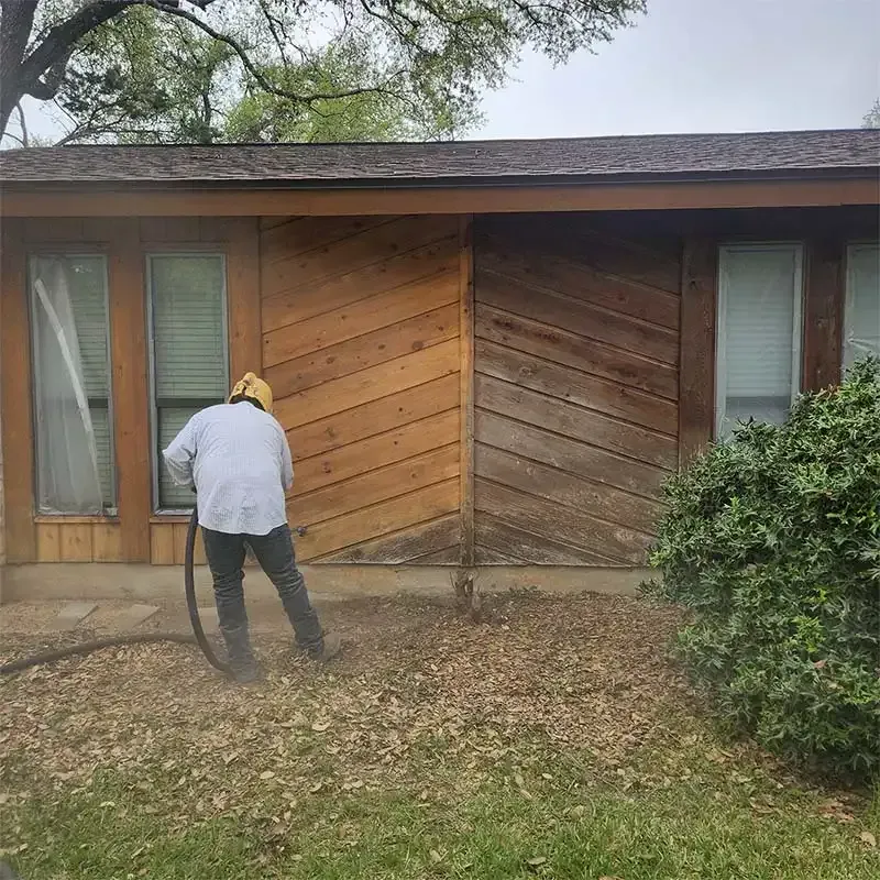 Technician sandblasting cedar siding on a ranch-style home