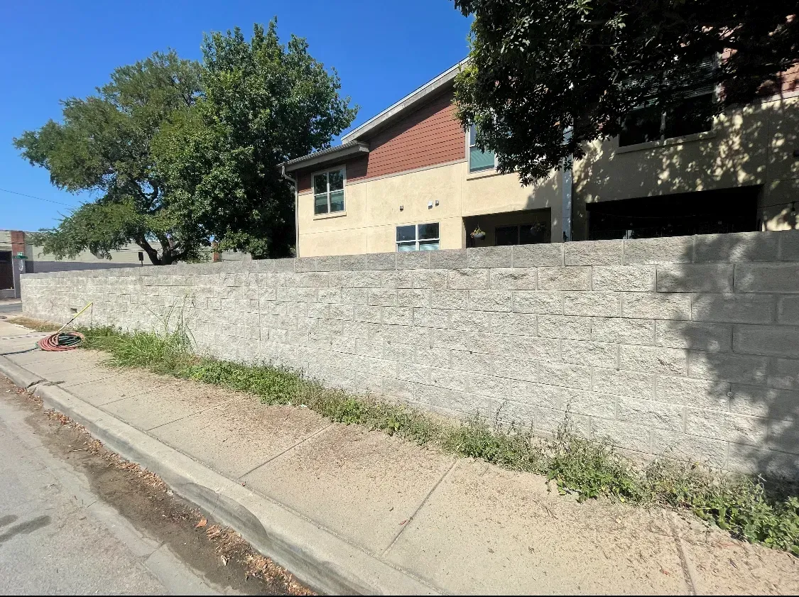 Long concrete block wall along a sidewalk after sandblasting