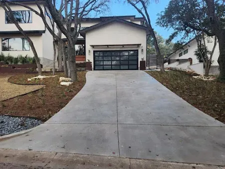 Smooth concrete driveway leading to a modern home after blasting