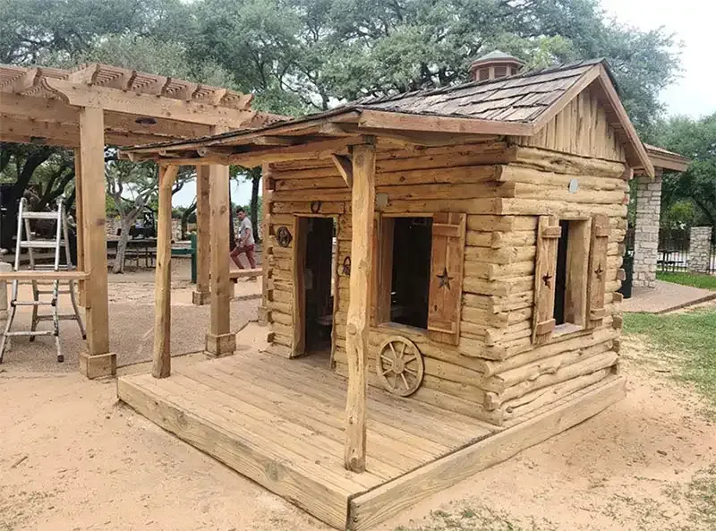 Restored wooden log-cabin playhouse with a covered porch