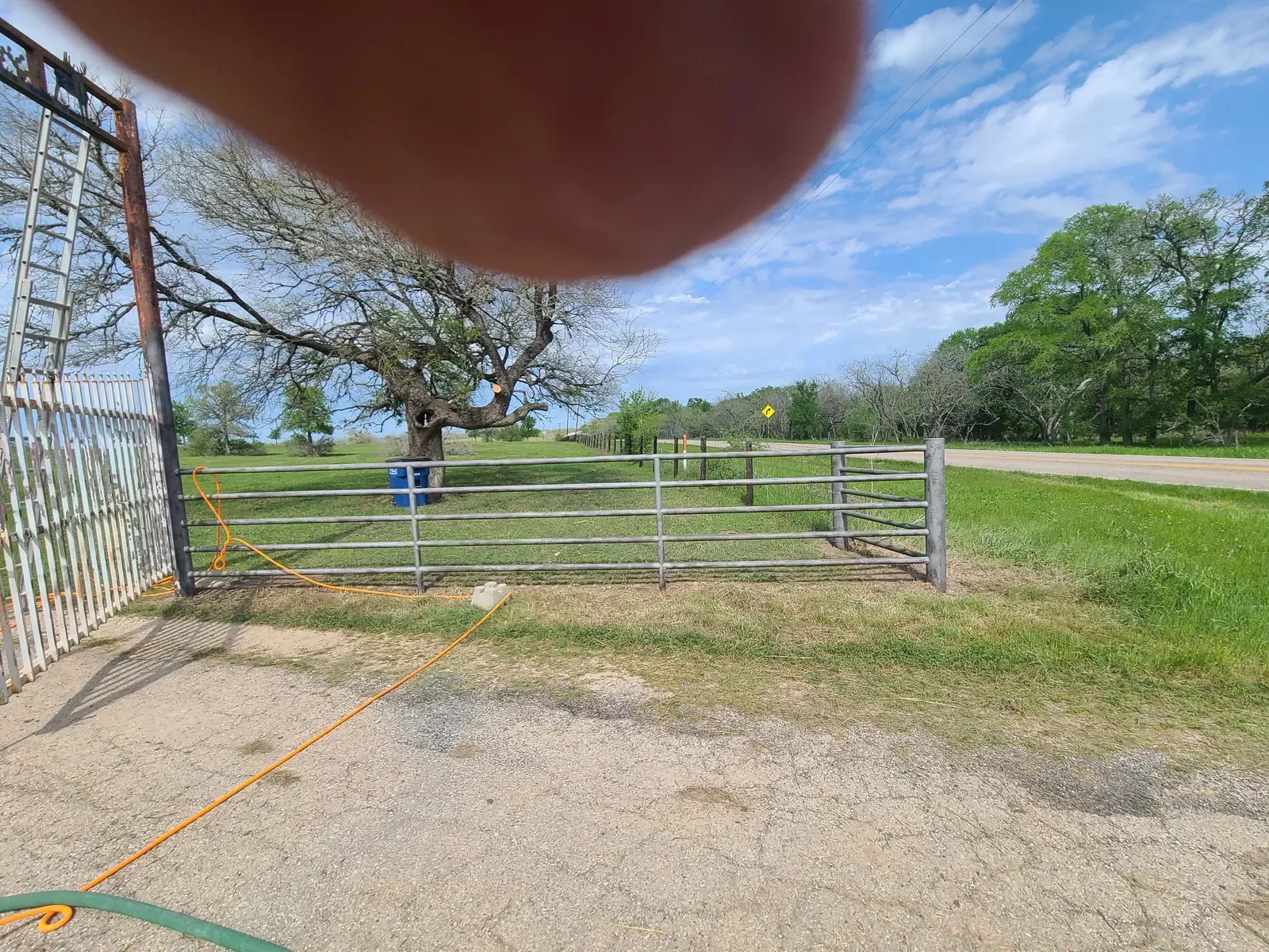 Ranch-style metal gate and driveway at a rural property