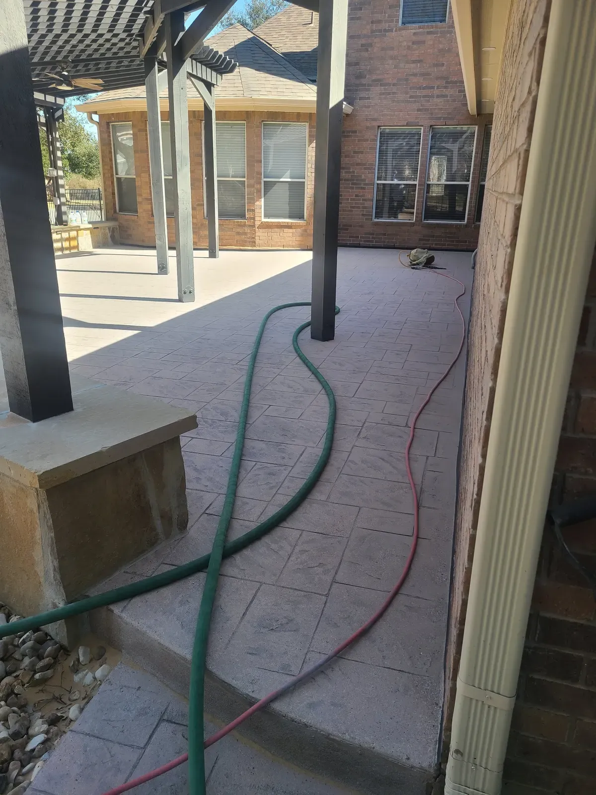 Stamped concrete patio beside a brick home during sandblasting