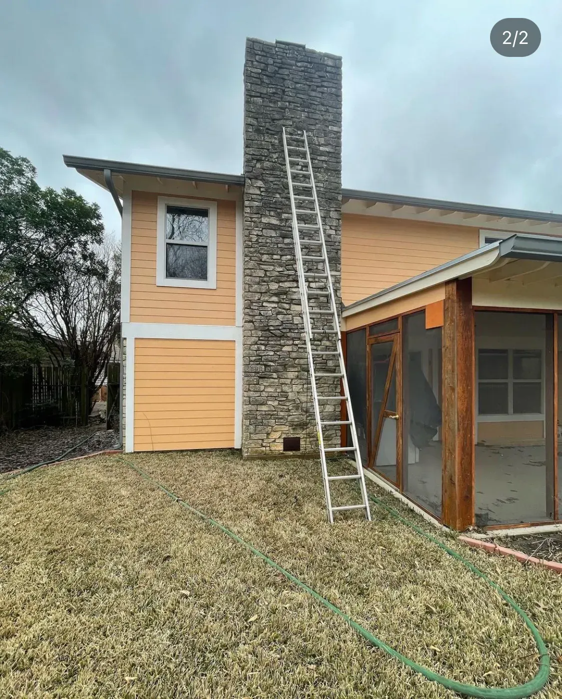 Ladder against a stone chimney on a home being sandblasted