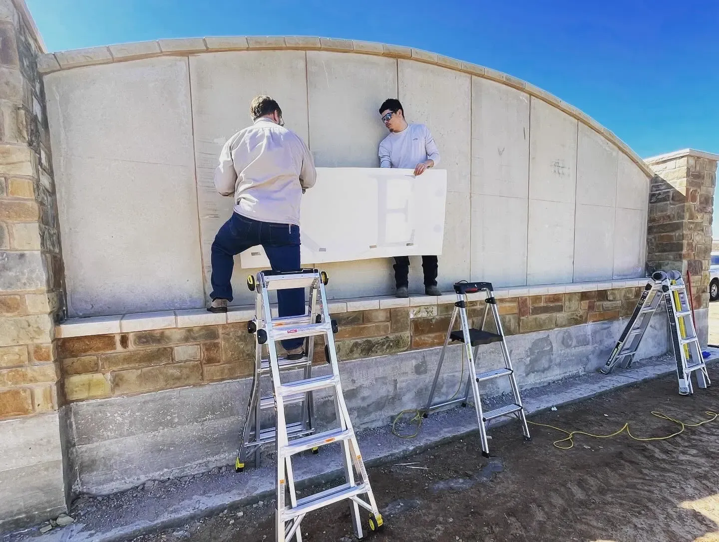 Workers on ladders restoring a curved stone entrance monument