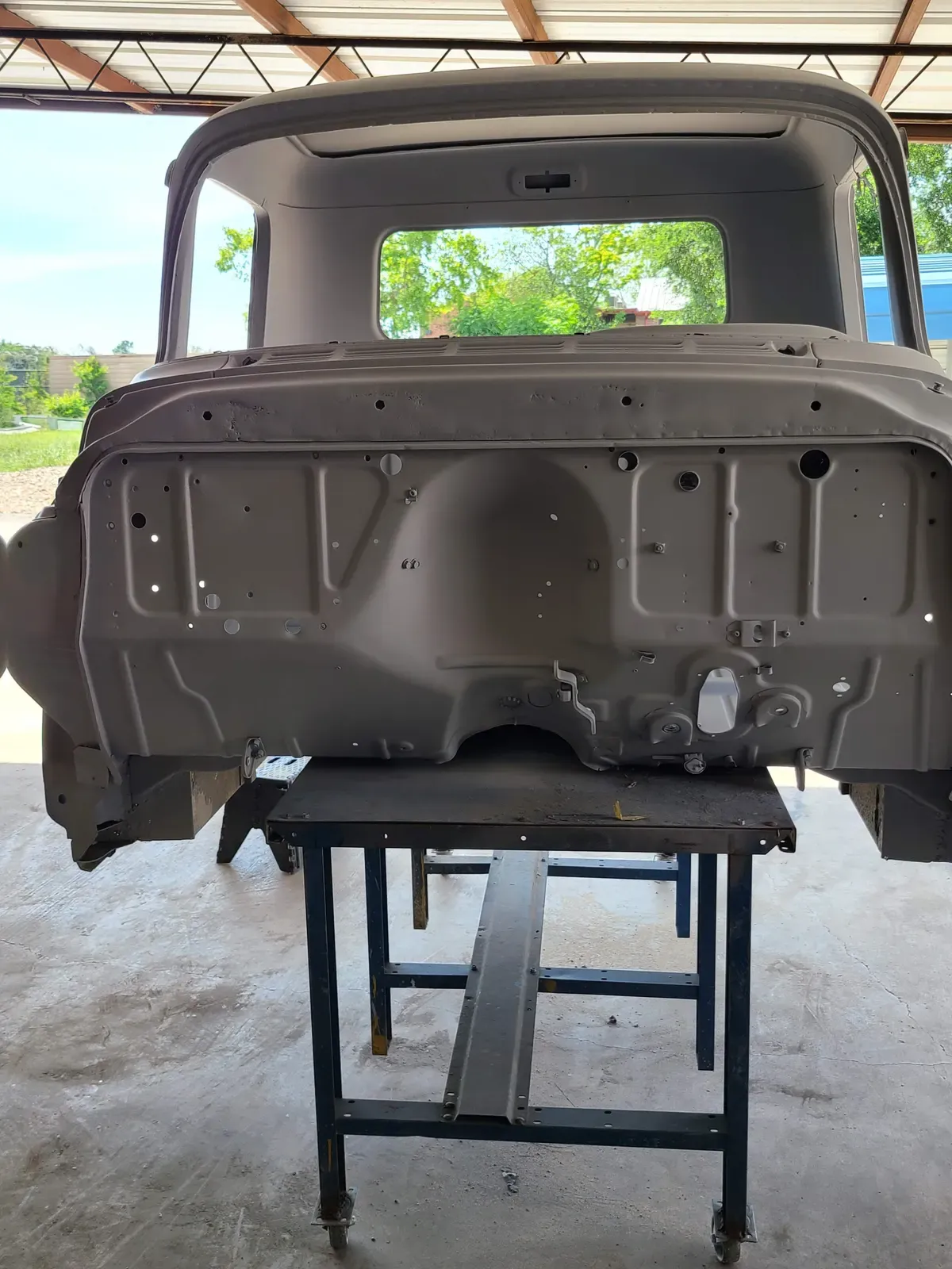 Vintage truck cab shell stripped to bare metal on a work stand