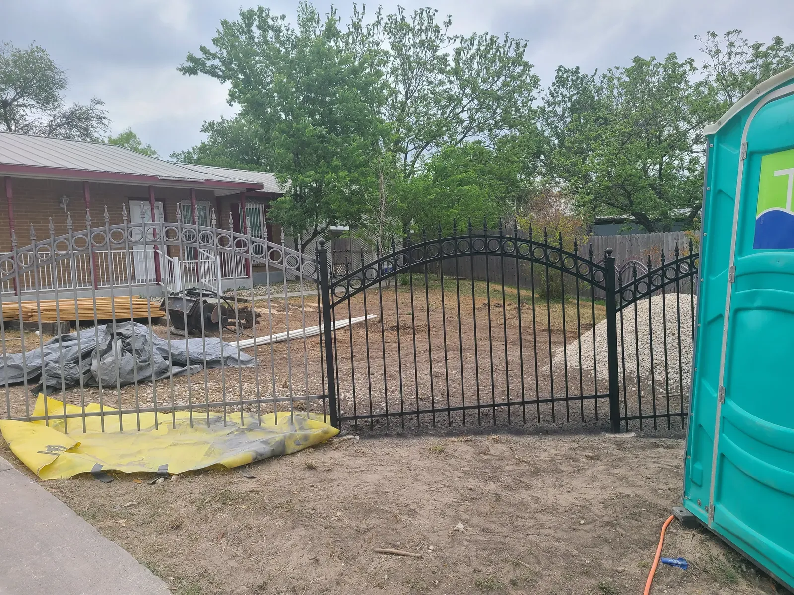Black wrought iron fence and arched gate after residential blasting